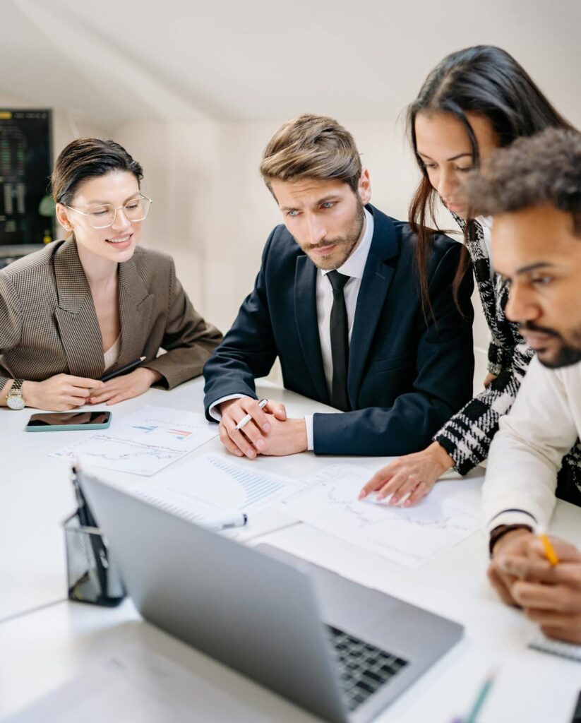 A diverse team of professionals engages in a collaborative office meeting, reviewing documents and strategies.